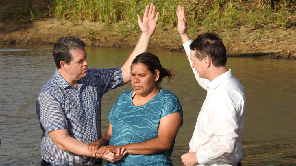 A woman being baptized in a river.