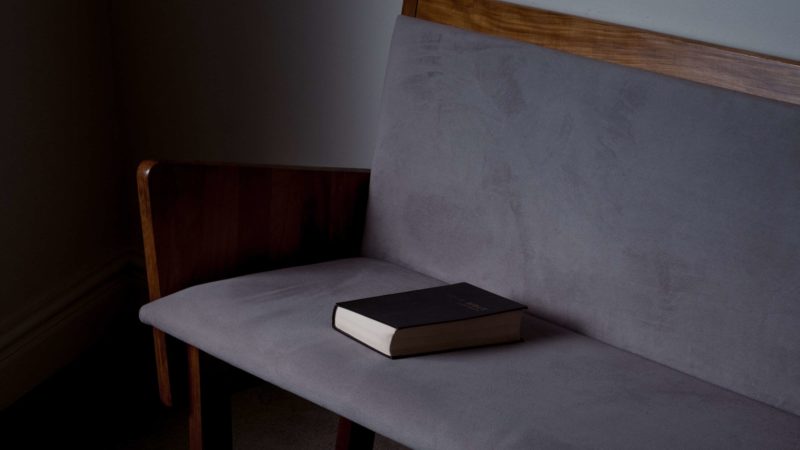 A Bible laying on a church pew. 