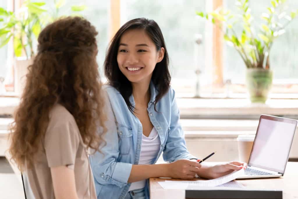 A young woman smiling at her friends while working on the computer. 