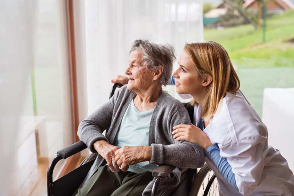 A nurse talking to an elderly woman in a wheelchair.