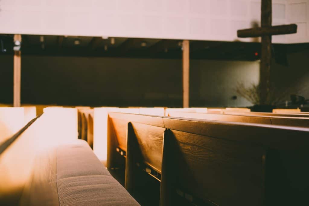 The inside of an empty church with a cross in the front corner.