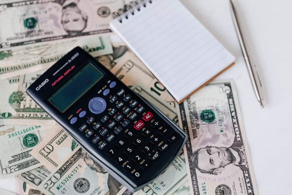 Una calculadora y un cuaderno de la colocación en el dinero.