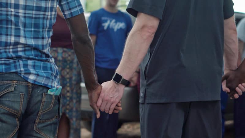 A group holding hands in prayer forming a circle, after a Bible study and prayer meeting session in a small group