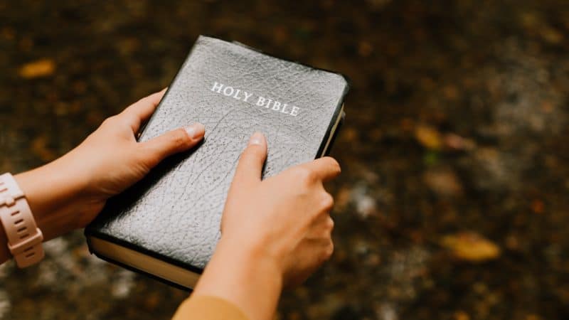 A person holding a Bible outside as we live daily by the Word of God and prepare ourselves to meet Jesus when He returns