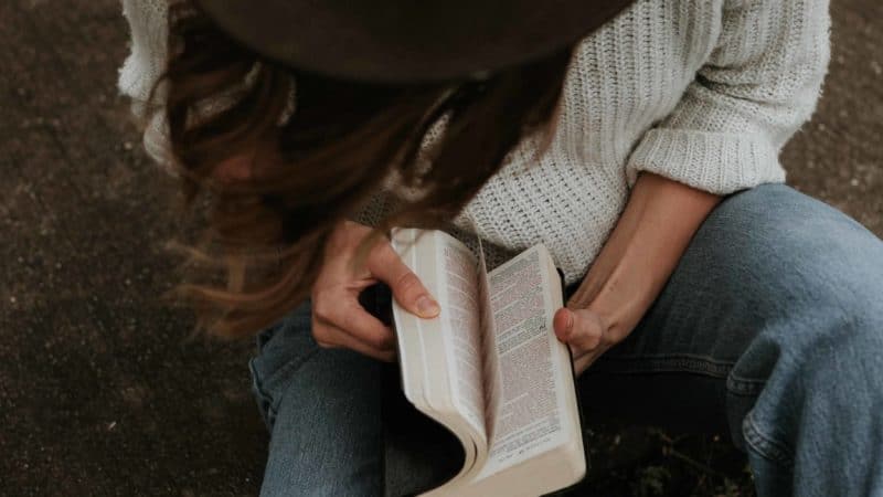 A woman sitting outside reading her Bible as we learn the importance of spending time in the Word of God