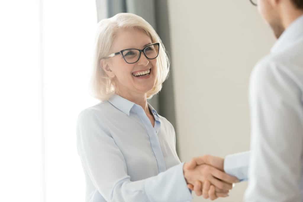 Happy older mature woman shaking hand of man