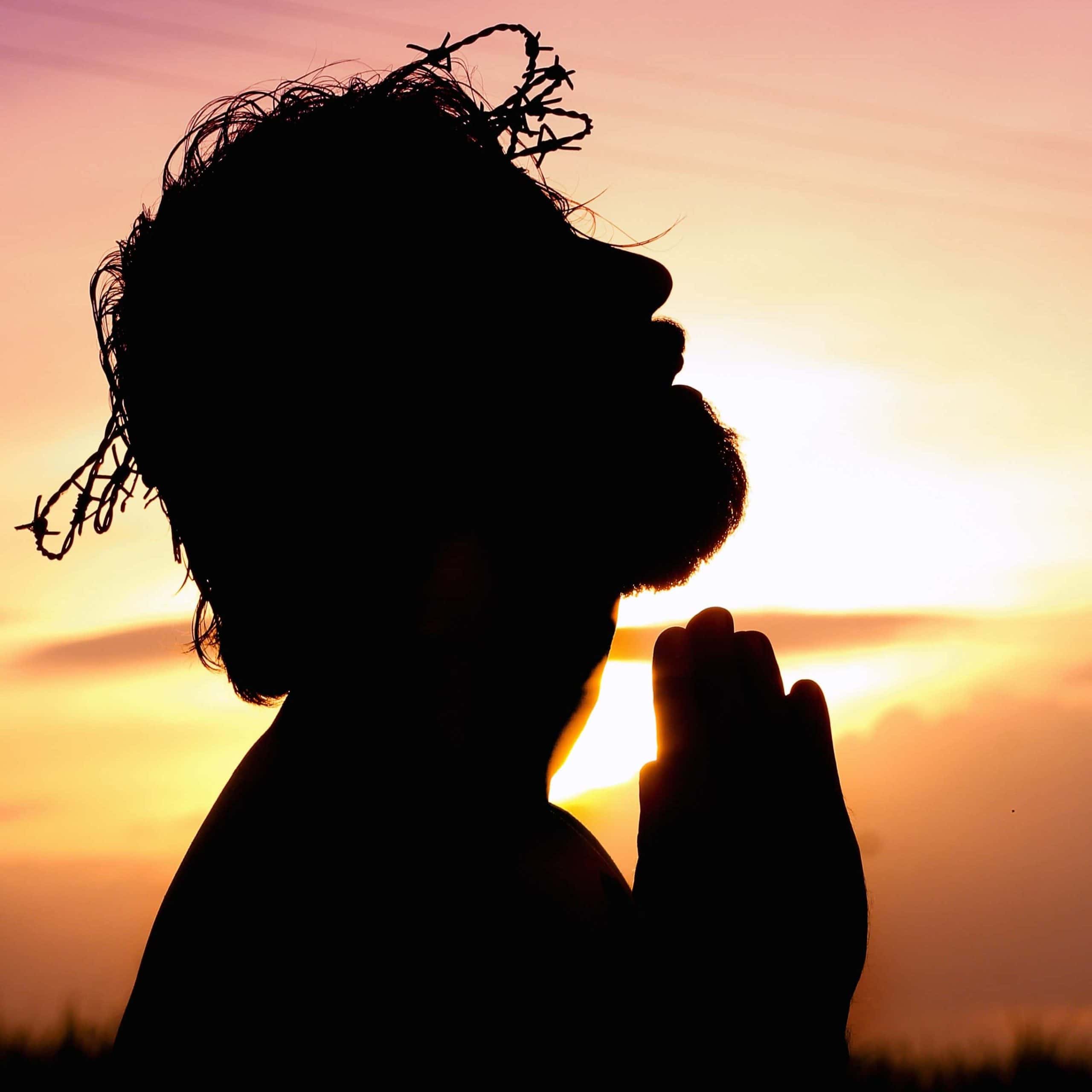 Silhouette of Jesus praying with crown of thorns on his head