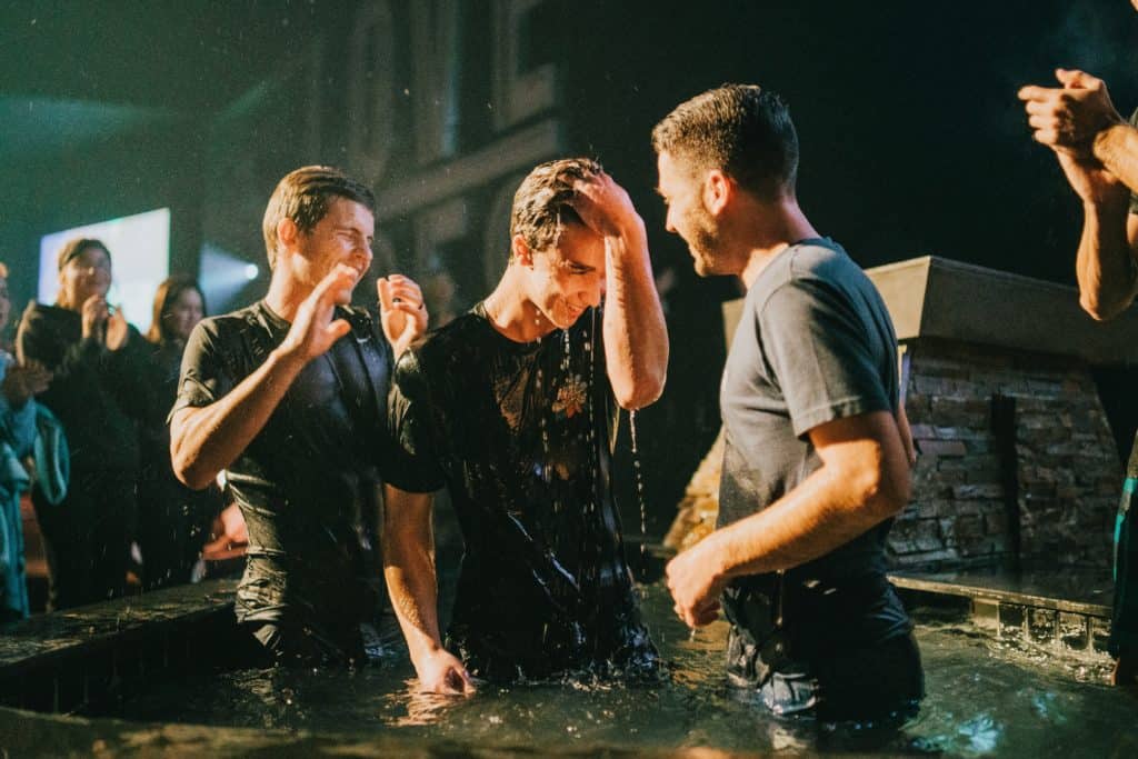 A young man getting baptized and people celebrating