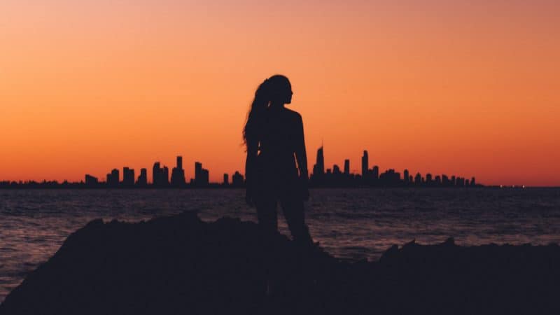 A silhouette of a woman looking at a city skyline at sunset as we learn about the Mission of God's Remnant Church