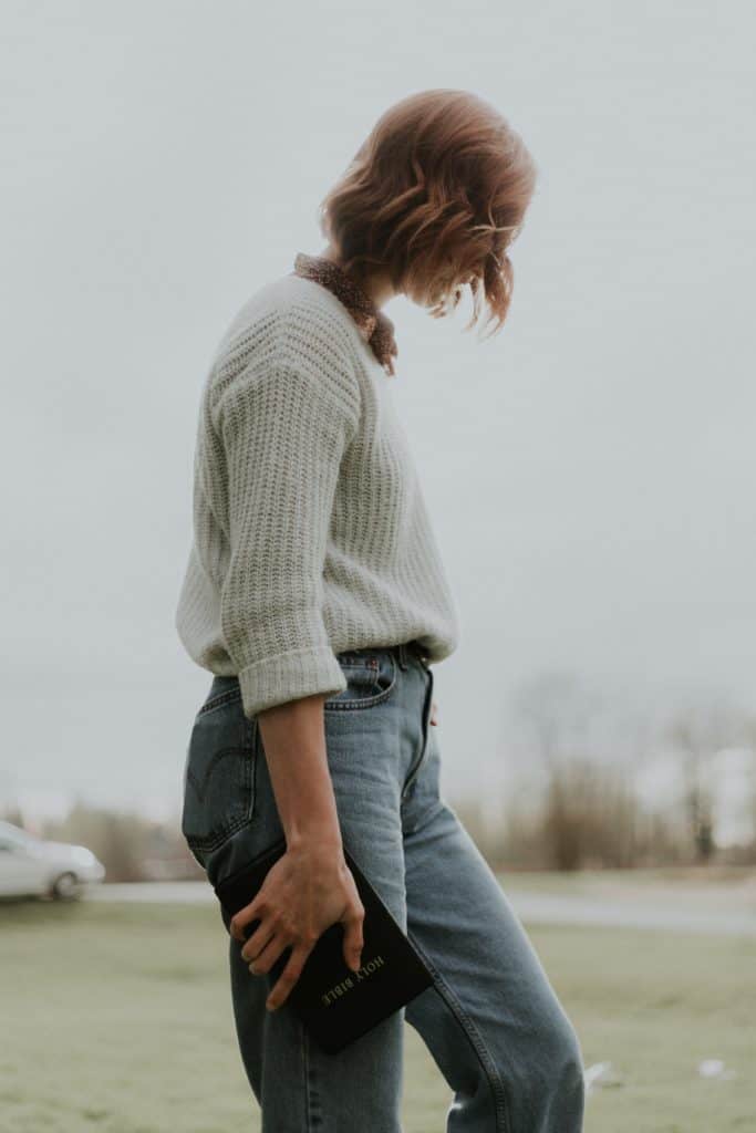 A young woman standing outside holding a Bible as we share the message of God's love in fulfillment of the God's Mission