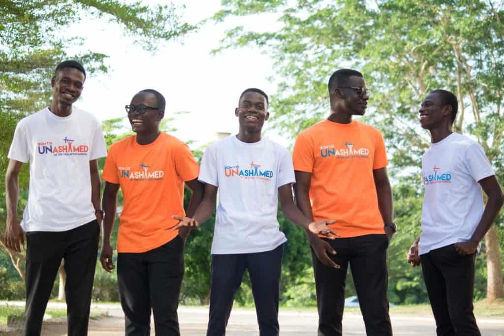 Five happy friends wearing shirts that say 'unashamed'