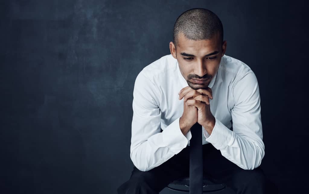 A young businessman looking thoughtful against a dark background