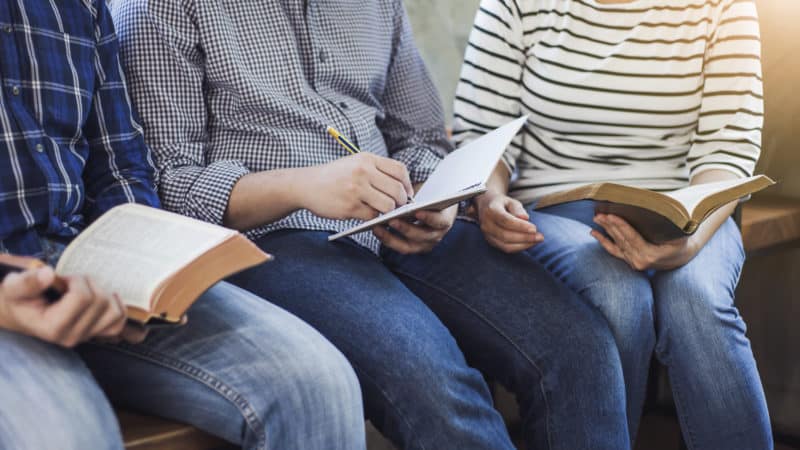 Close up of Christian group reading and studying the Bible together as Bible mentions of small groups