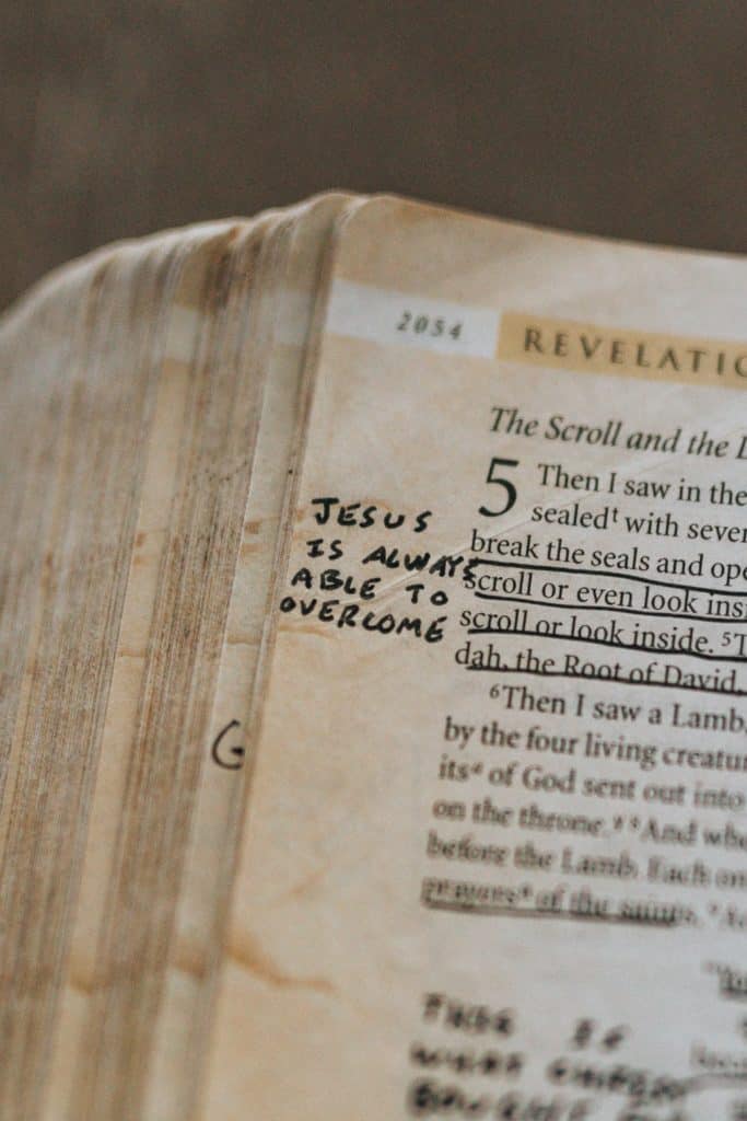 The Bible open to Revelation 5:2 with 'Jesus is always able to overcome' written in the margin.