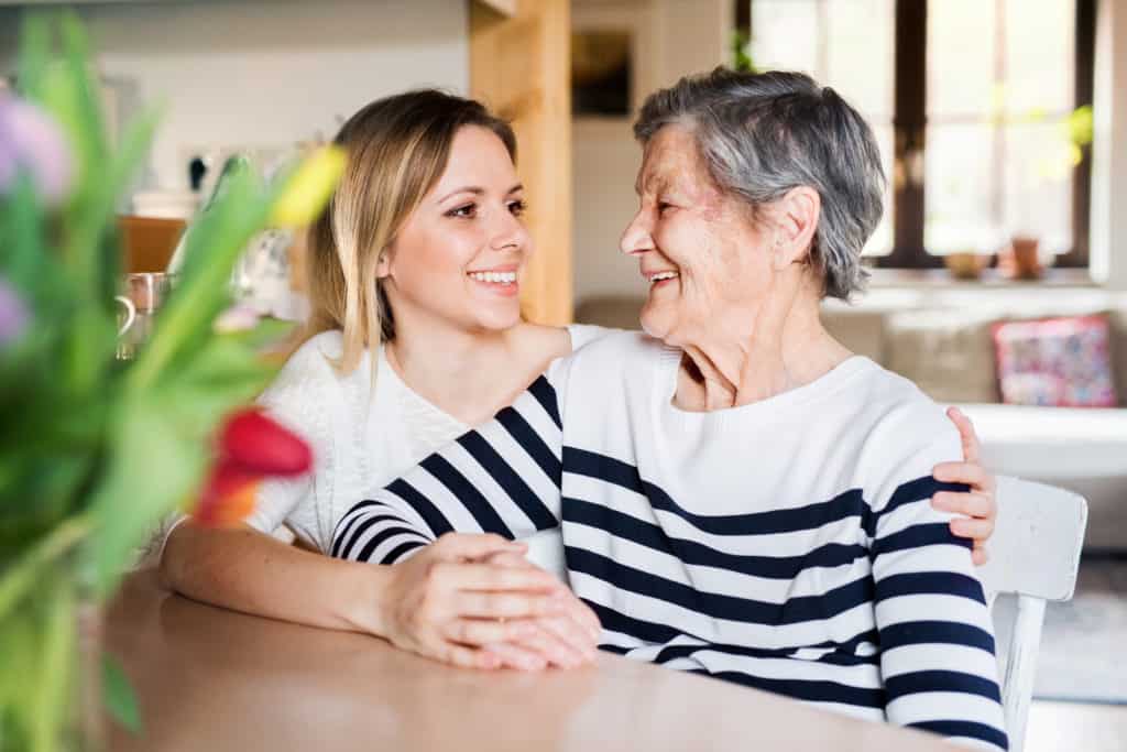 Portrait of an elderly grandmother with an adult granddaughter at home.