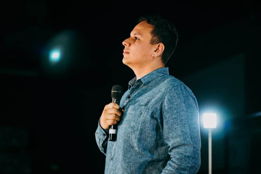 A young pastor standing confidently with a microphone.