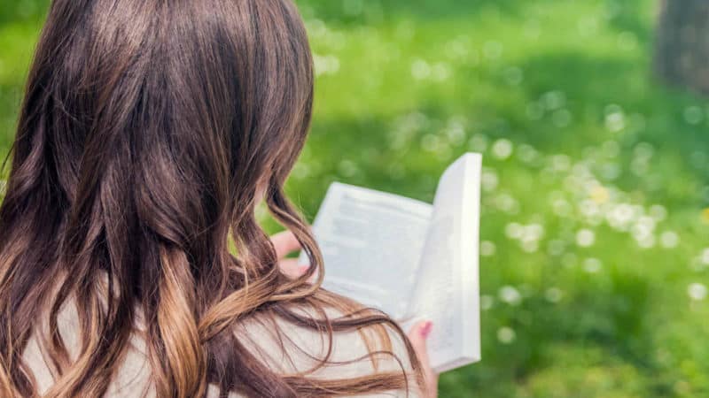 A woman reading a book outside as we learn the meanings of the symbols used in prophecies and let Bible interpret itself