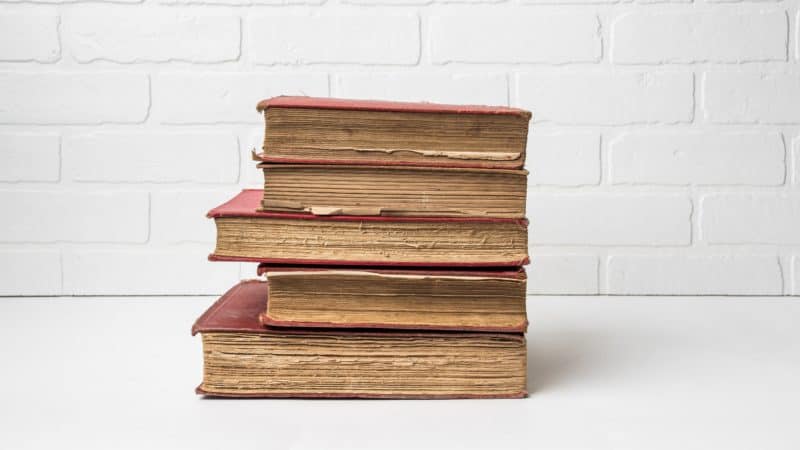 A stack of old books on a white table.