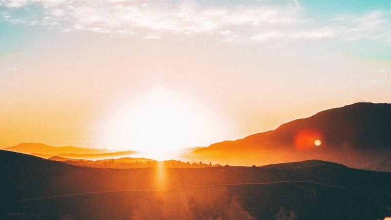 The sun setting over a beautiful hilly landscape as we study about the new earth and new heaven in the Scripture