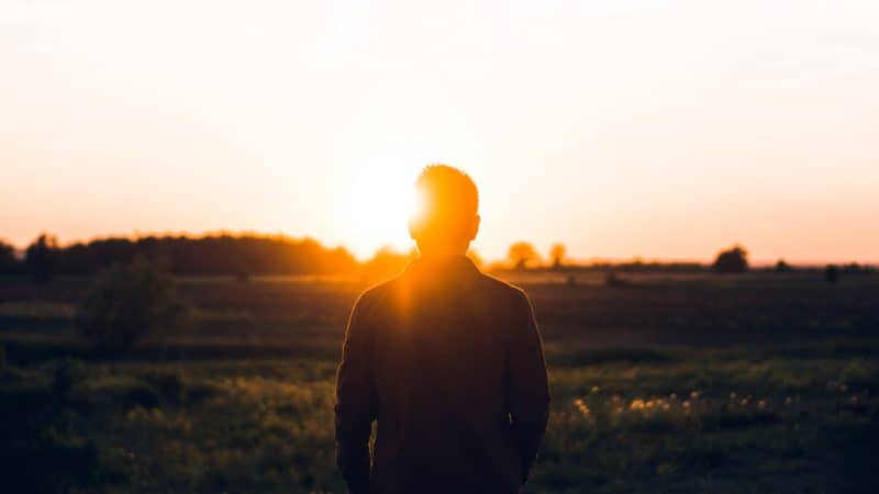 Un hombre mirando la puesta de sol al estudiar acerca de la Nueva tierra en el contexto de la gran imagen de la salvación de la raza humana