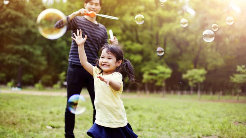 Father and daughter having fun in park with Soap Bubbles as we study the importance of spending quality time with children