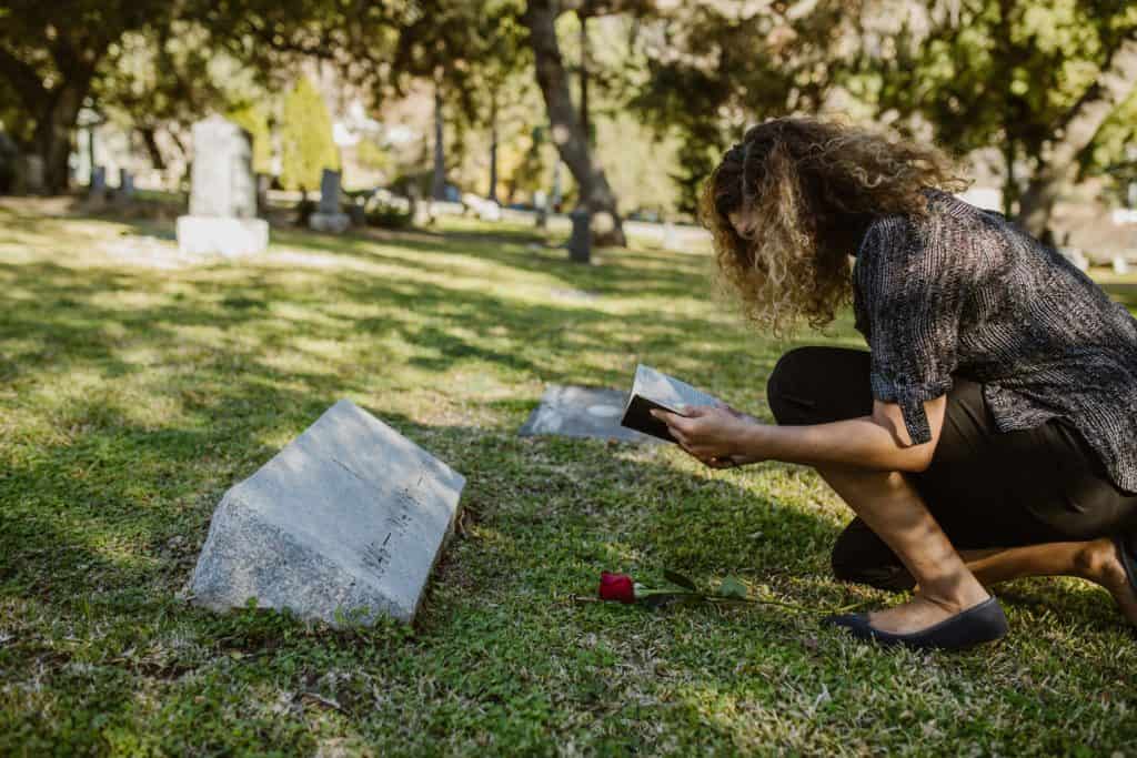 A woman reading a Bible at a grave.