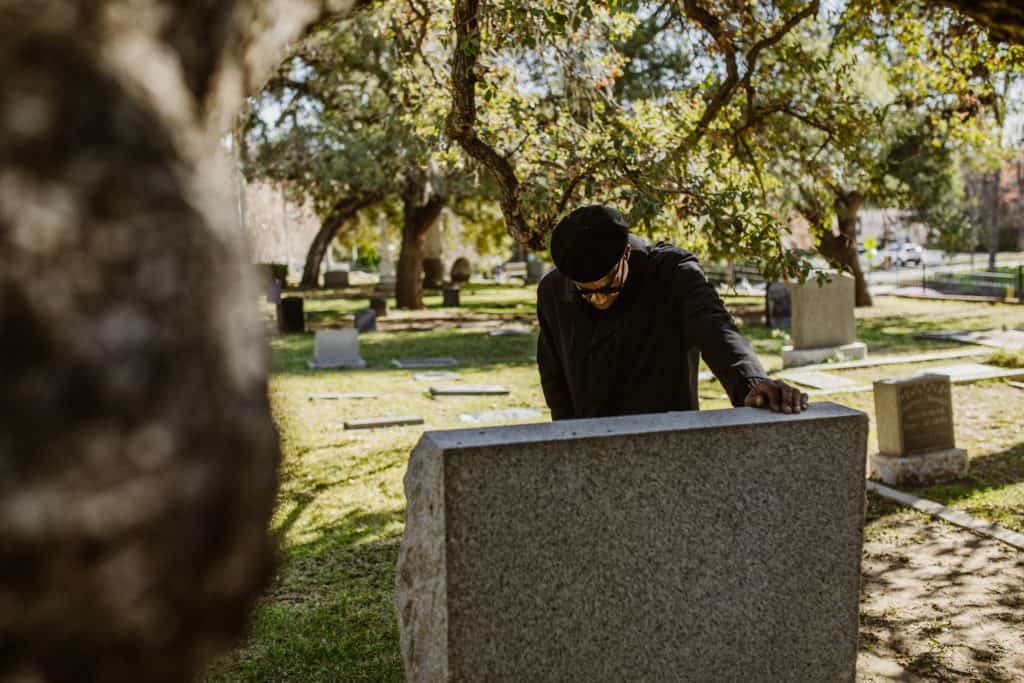 A man grieving at a grave.