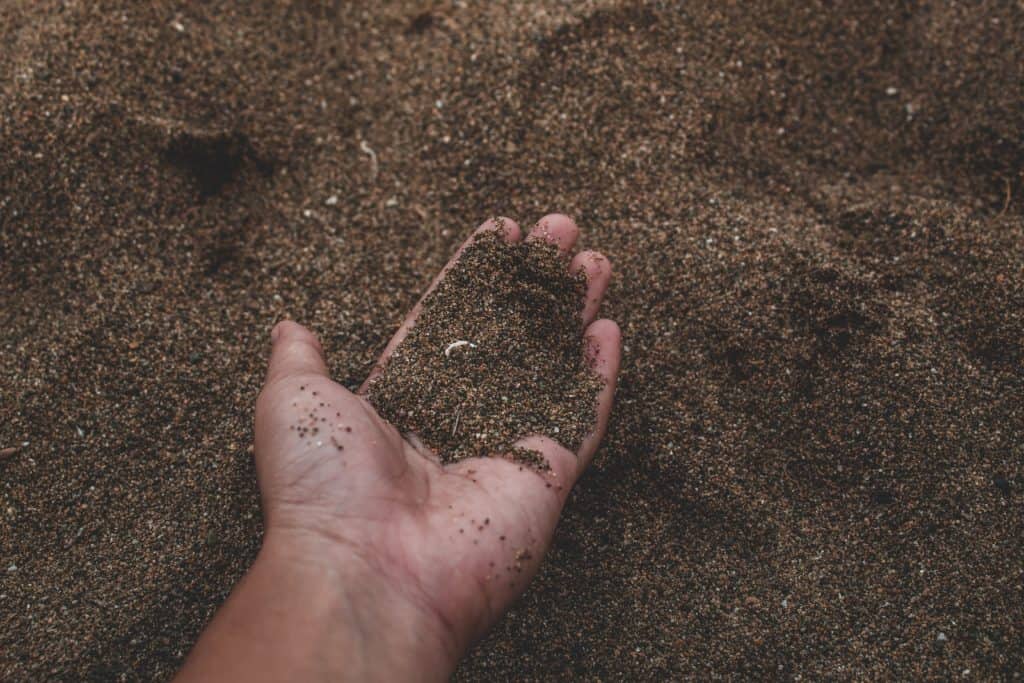 A person holding a handful of sand.