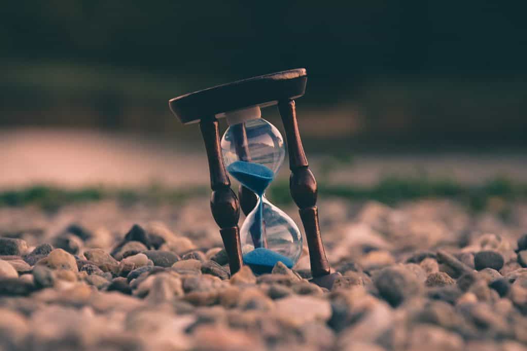 An hourglass on a rocky ground.