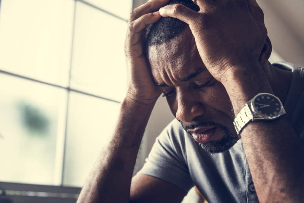 Stressed man sitting with his hands on his head.