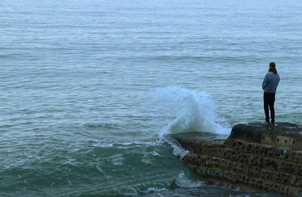 A man standing by the ocean looking out.