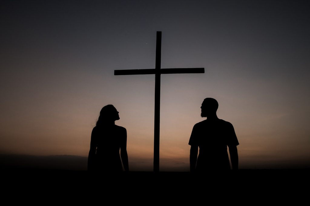 Silhouettes of a man and a woman looking at the cross. 