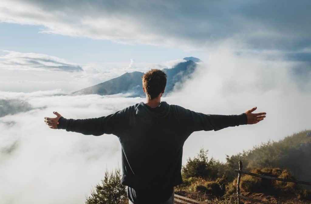 A man at the top of a mountain with his arms outstretched.