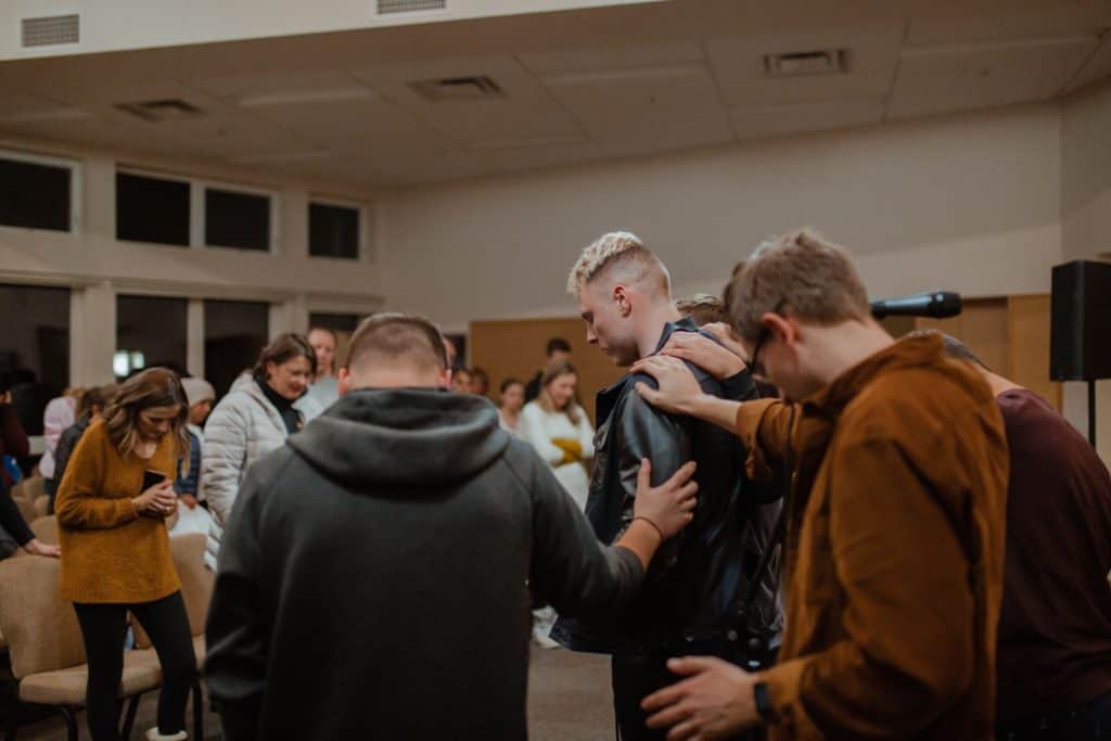 A group of people at a church praying for someone with their hands on him.