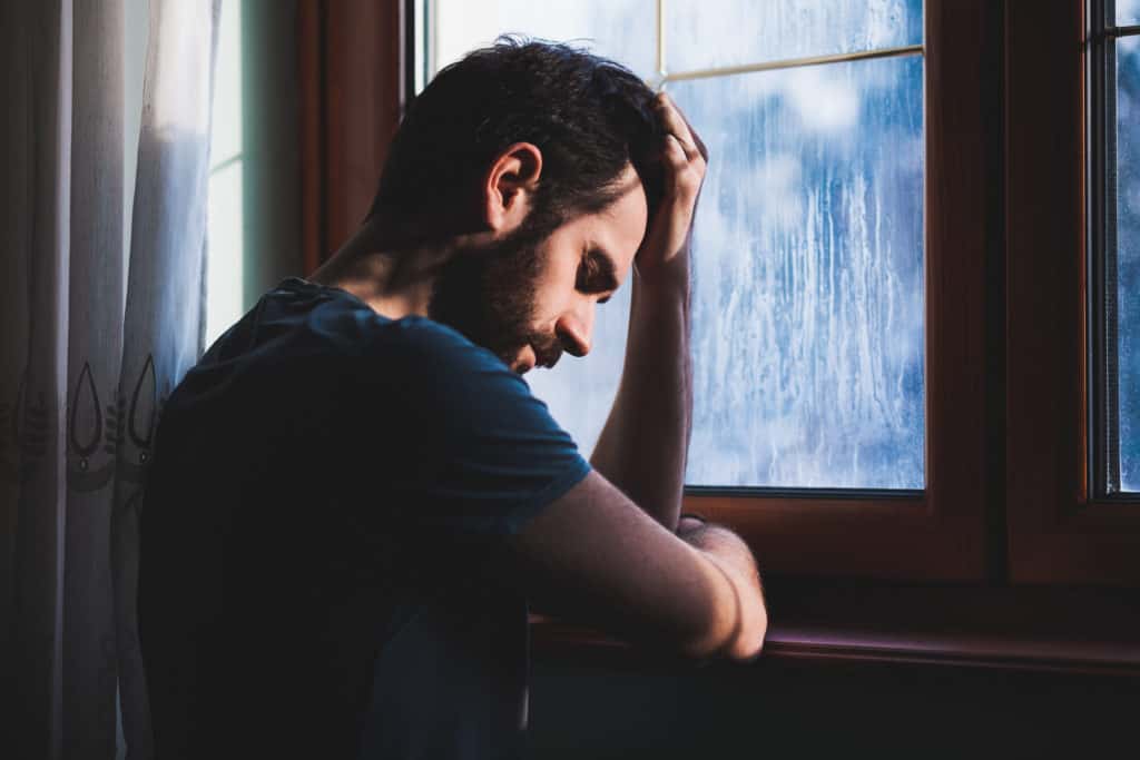 Man in personal prayer alone by a window.