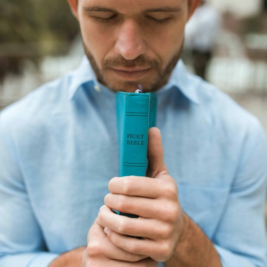 A man holding a Bible praying for understanding about a Scripture.