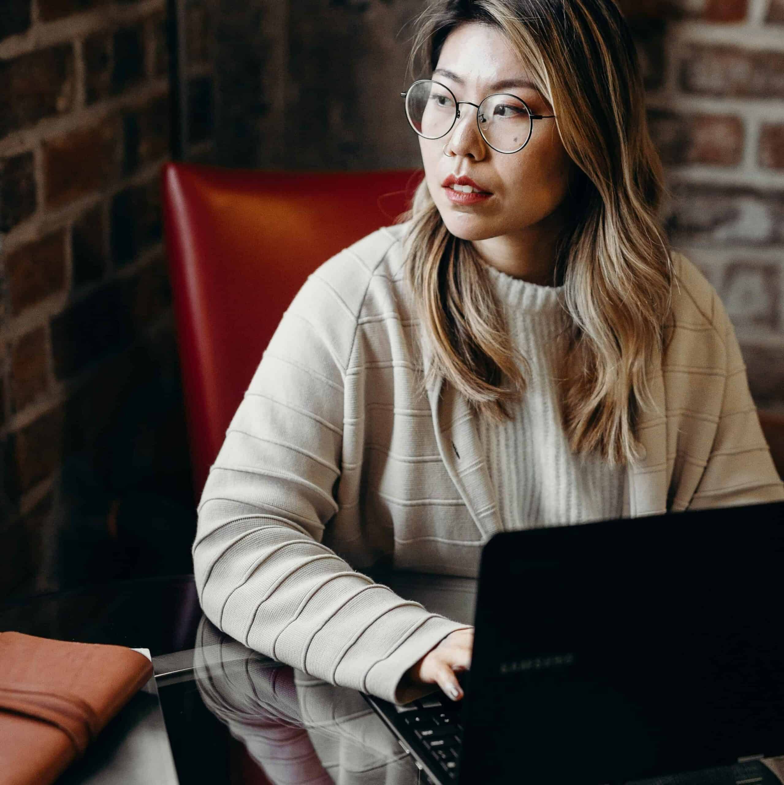 A woman working on her computer and looking out of the window.