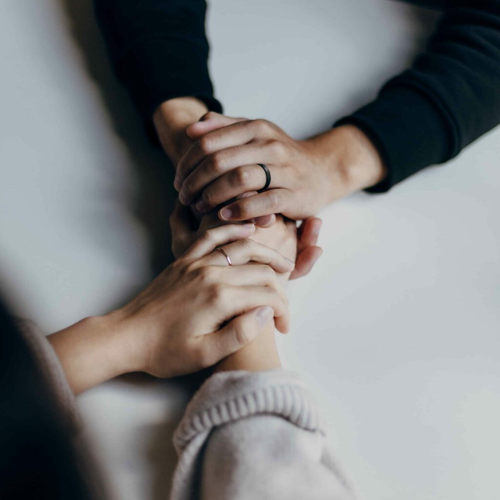 A husband and wife holding hands on a table as they pray together.