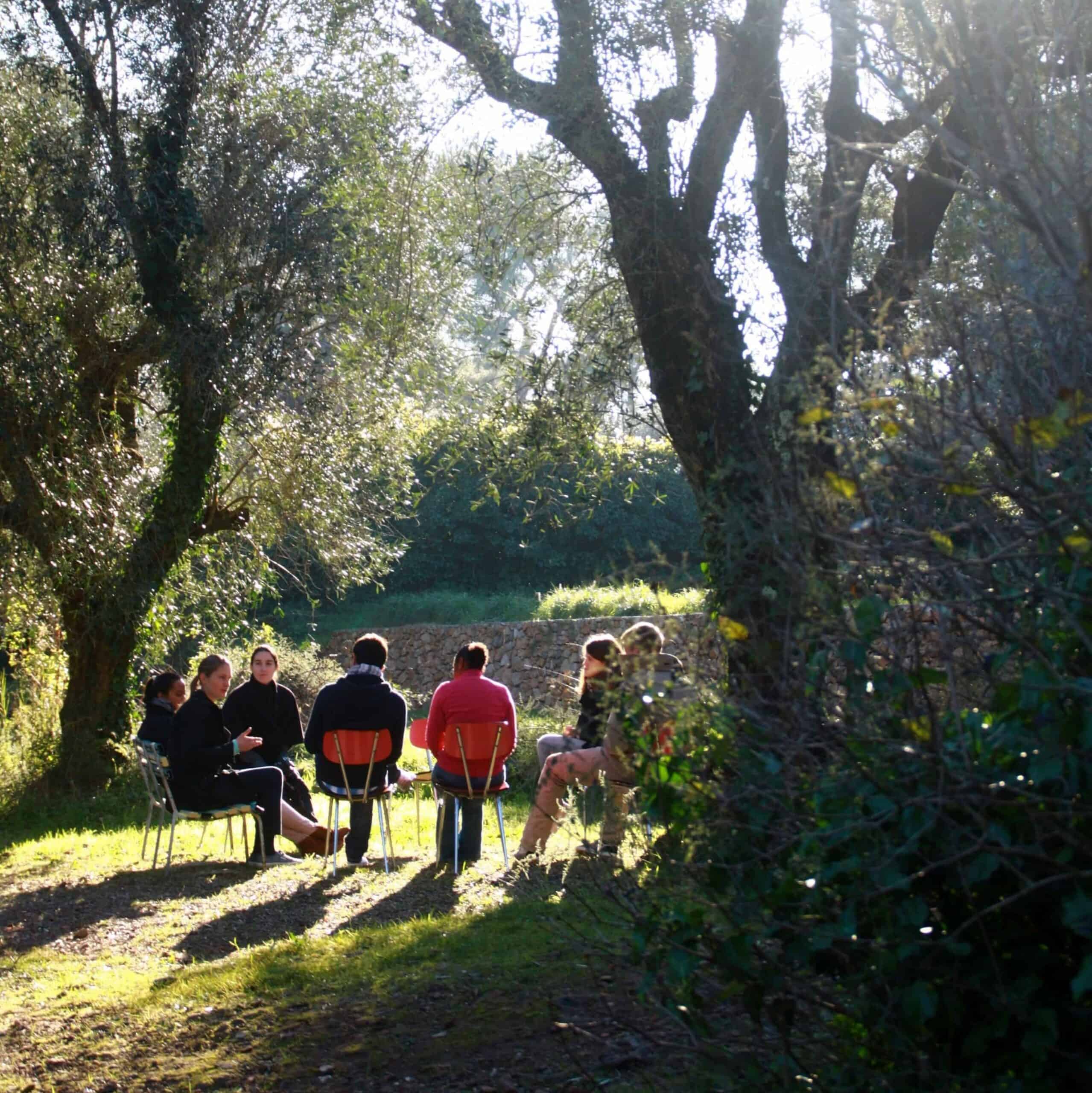 A prayer group sitting in chairs outside in a circle.