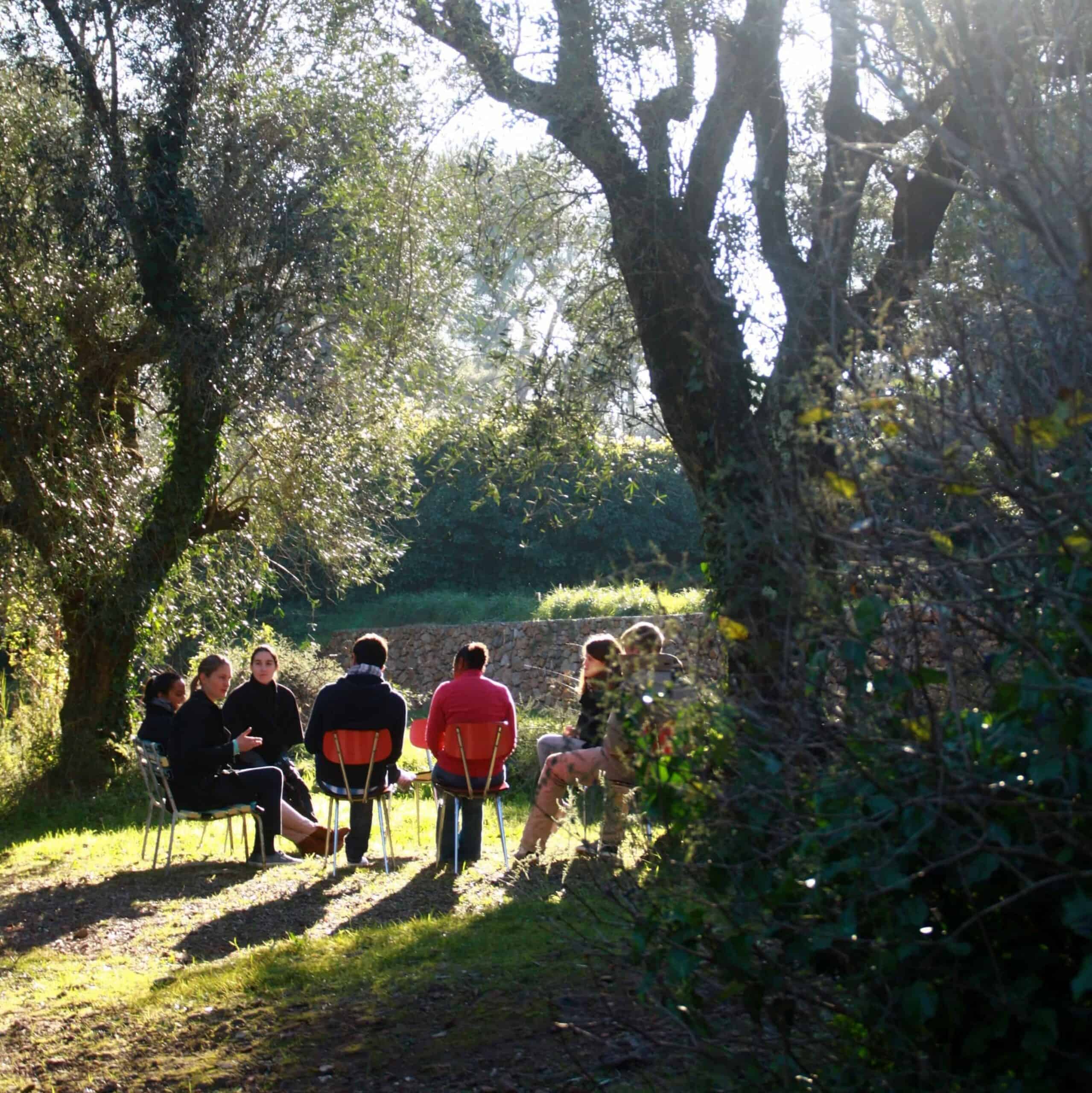 A prayer group sitting in chairs outside in a circle. 