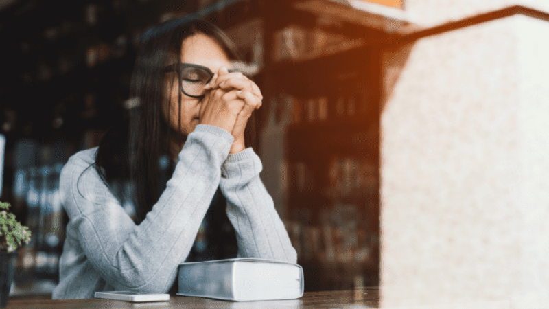 Woman sitting in a window, praying.