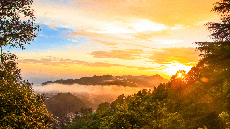 Mountain landscape with sun setting in the background.