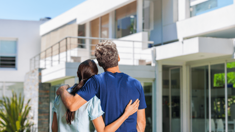 Man and woman standing together facing a building. 