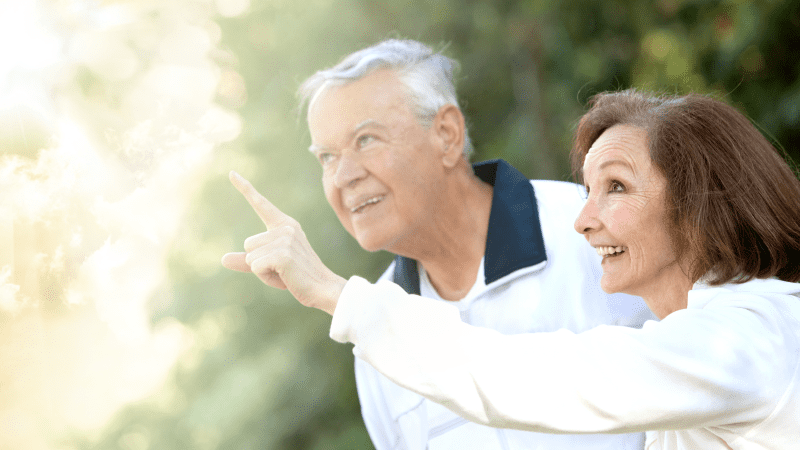 A woman and a man standing together looking up at what the woman is pointing to. 