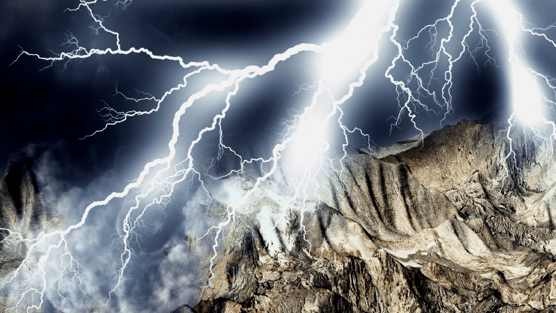 Many lightning strikes on a hill top viewed from above the hills near the lightning. 