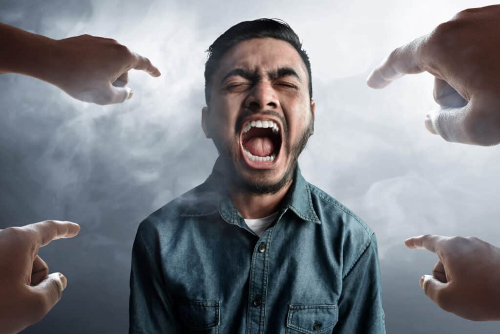 Man screaming with 4 hands pointing at him. 