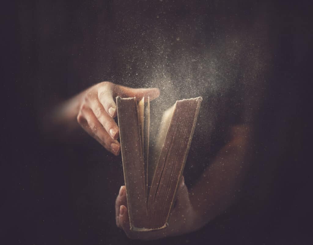 Hands open a dusty book.