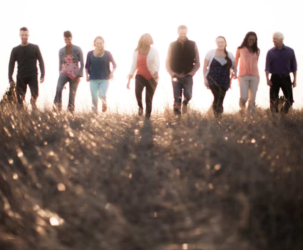 Group of people walking towards the camera with light shining behind. 