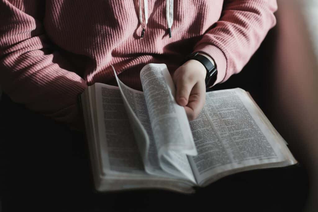 Person holding Bible flipping through pages.