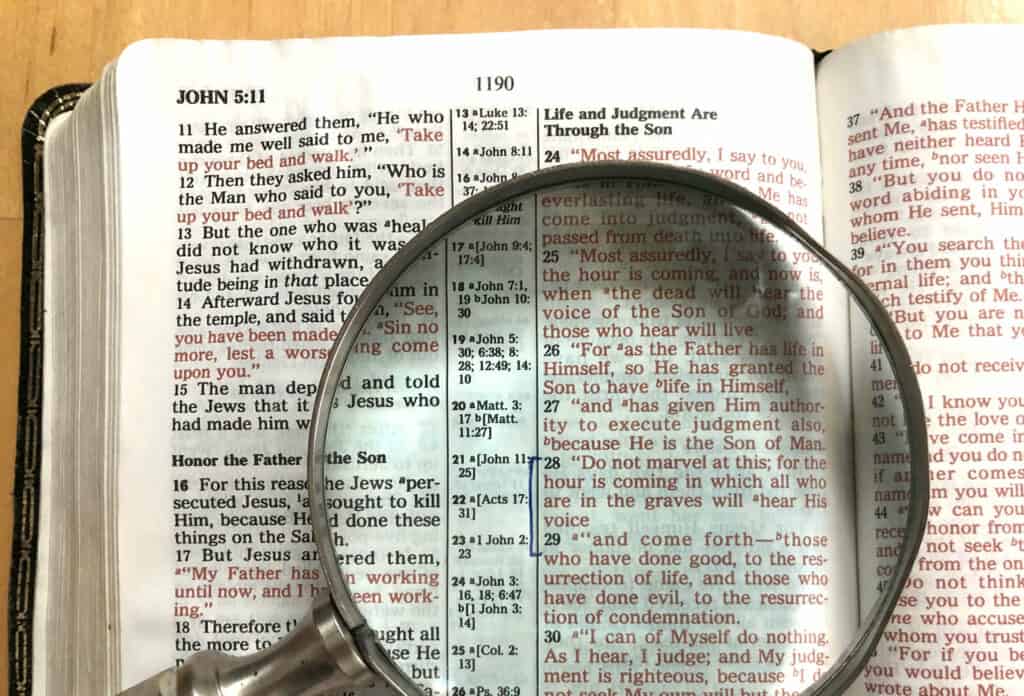 A magnifying glass laying on a Bible opened to John. 